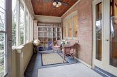 enclosed sitting area in front of house with wicker chairs