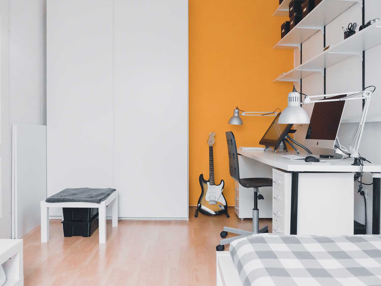 brown and black stratocaster guitar leaning on yellow wall inside room