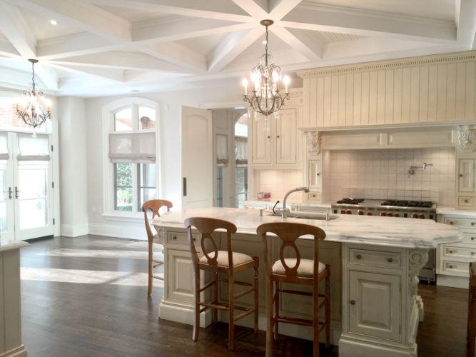 bright white kitchen with island and chandeliers