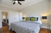 bed with green pillows and black ceiling fan in bedroom