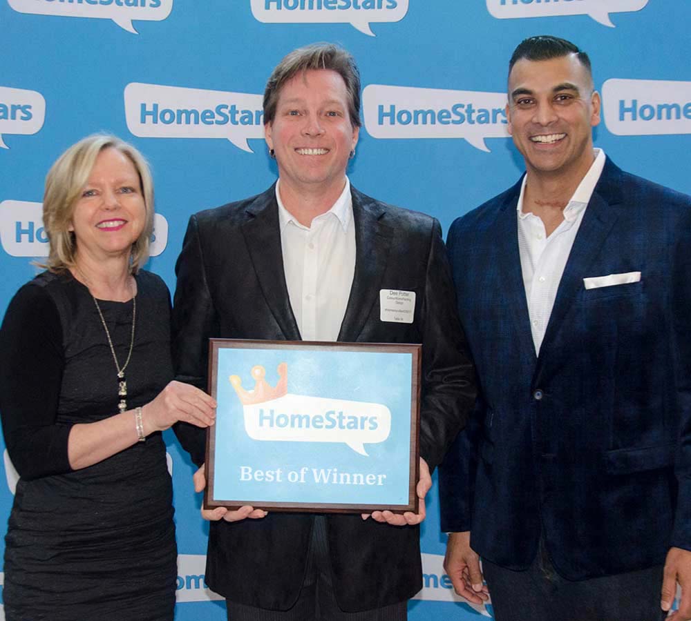 two smiling men standing beside woman holding framed homestars best of winner award