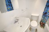 white toilet bowl and sink with shower curtain decorated with fish illustrations