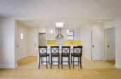 white kitchen interior with four black chairs lined up in front of island